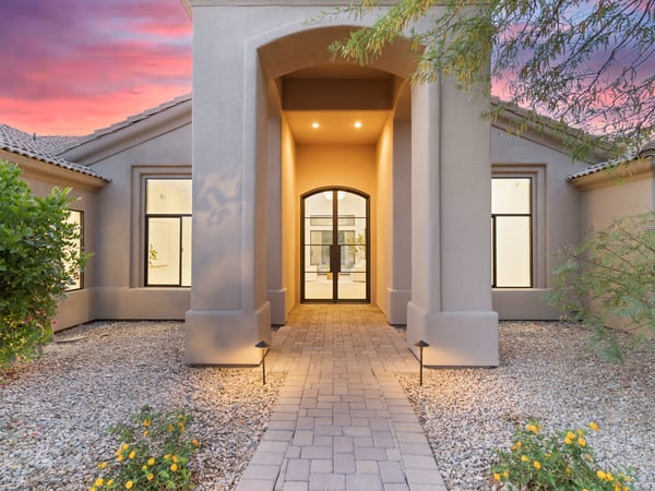 Dramatic front entrance with soaring architectural columns, paver walkway, and stylish glass doors. The welcoming entry introduces the sophisticated finishes found throughout this luxury Scottsdale home.