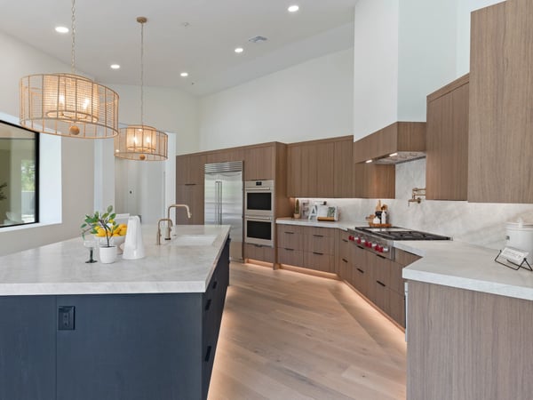 Sophisticated gourmet kitchen with a large waterfall island, Wolf range, Sub-Zero refrigerator, custom cabinetry, quartz countertops, and designer lighting. An ideal space for cooking and entertaining.