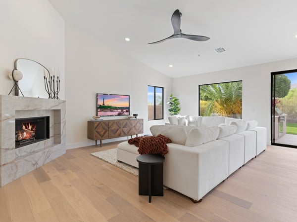 Elegant family room highlighted by a modern fireplace, soaring ceilings, oversized windows, and beautiful backyard views. Designed for comfortable living and effortless entertaining.