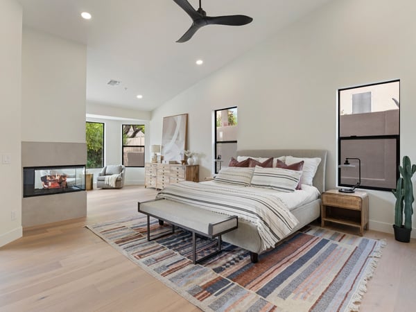 Spacious owner's suite with soaring ceilings, a contemporary fireplace, sitting area, and beautiful backyard views. Thoughtfully designed for luxury, comfort, and everyday living in this Scottsdale home.
