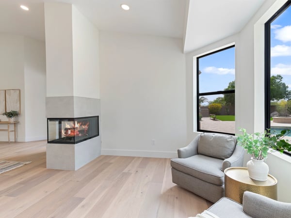Comfortable sitting space adjacent to the primary bedroom featuring a sleek fireplace, oversized windows, and tranquil outdoor views. Perfect for reading, relaxing, or enjoying quiet mornings.