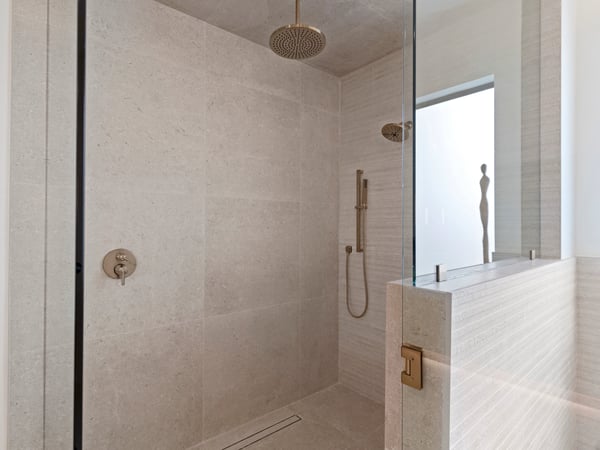 Oversized walk-in shower with premium tile finishes, frameless glass enclosure, rainfall showerhead, and luxury fixtures. Designed to deliver a relaxing spa-like experience.