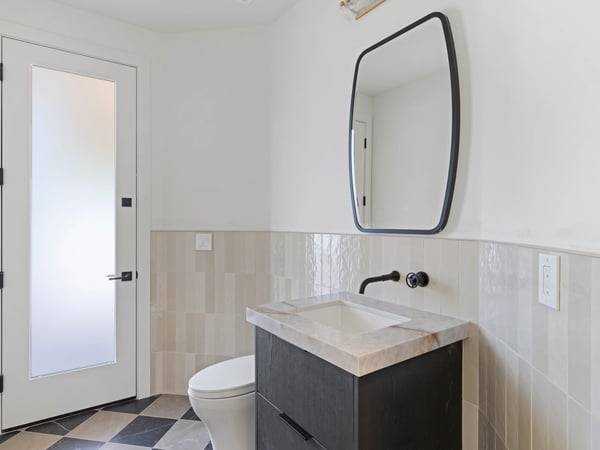Contemporary guest powder room featuring a floating vanity, premium stone countertop, designer mirror, and sleek black fixtures. Thoughtful finishes complement the home's modern Scottsdale design.