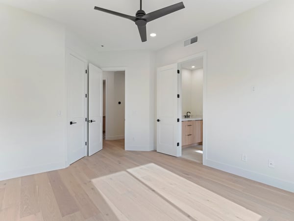 Comfortable guest bedroom with wide-plank flooring, modern ceiling fan, and direct access to a private bath. This Scottsdale home offers bright living spaces and premium finishes throughout.