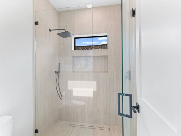 Beautiful guest shower featuring floor-to-ceiling tile, frameless glass enclosure, rainfall showerhead, and contemporary fixtures. A refined upgrade that complements this Scottsdale home's luxurious design.