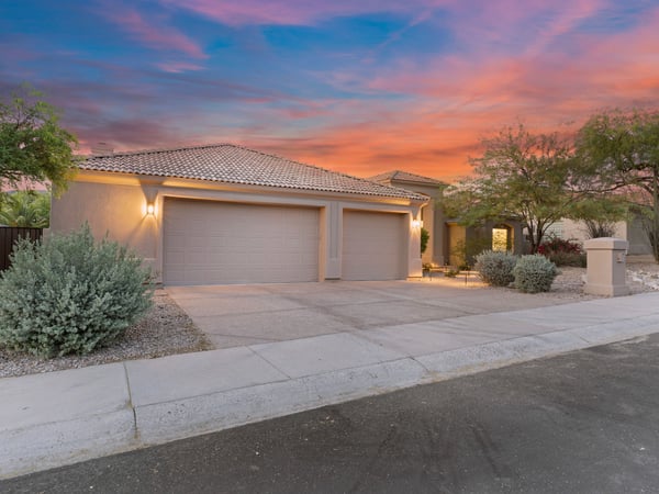 Welcoming front exterior featuring a spacious three-car garage, attractive desert landscaping, and timeless curb appeal. This Scottsdale residence blends elegance with everyday functionality.