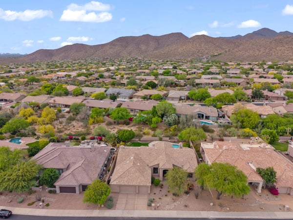 Sweeping aerial perspective capturing the Scottsdale neighborhood, nearby mountain scenery, mature desert landscaping, and the home's desirable residential setting.