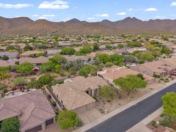 Elevated aerial showcasing the surrounding Scottsdale neighborhood, scenic mountain vistas, and the home's excellent location among beautifully maintained residences.