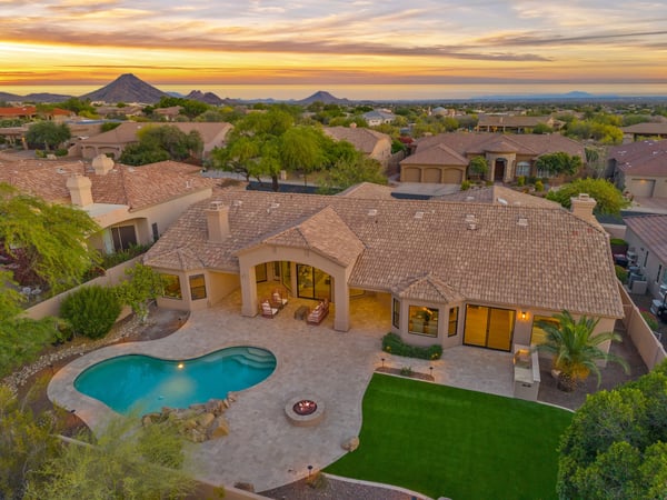 Stunning overhead view of the backyard featuring a sparkling swimming pool, custom outdoor entertaining areas, built-in BBQ, expansive travertine patio, and professionally landscaped grounds in Scottsdale.