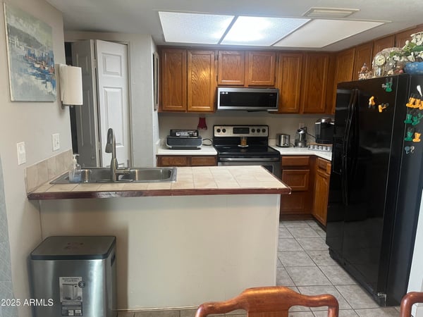 Well-appointed kitchen features extensive cabinet storage, black appliances, tile counters, and a convenient breakfast bar that opens to the main living area for effortless entertaining.