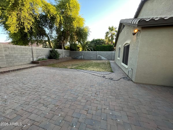 Generous backyard offers a spacious paver patio, grassy area, raised planter beds, and privacy walls, providing endless possibilities for entertaining or outdoor enjoyment.