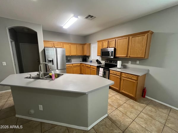 Spacious kitchen showcases oak cabinets, stainless steel appliances, a center island with breakfast bar, and an open layout ideal for cooking, entertaining, and gathering with family.