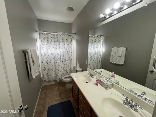 Full bathroom showcasing a spacious dual-sink vanity, large mirror, and tub/shower combination, providing practical convenience for family members and guests.