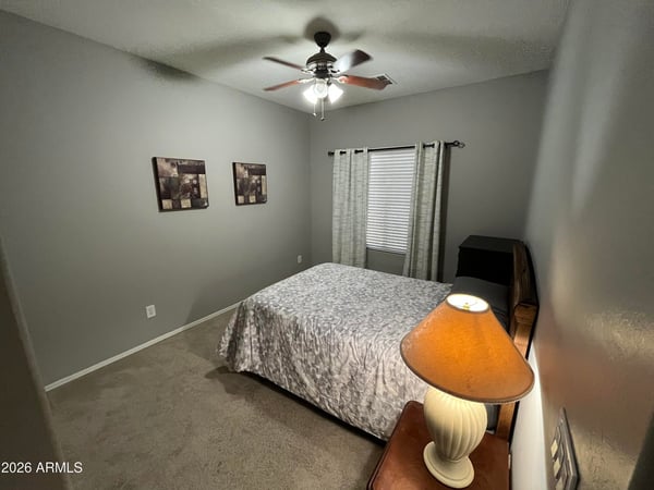 Secondary bedroom with neutral d cor, ceiling fan, and ample floor space, offering flexibility for guests, a home office, or a hobby room.