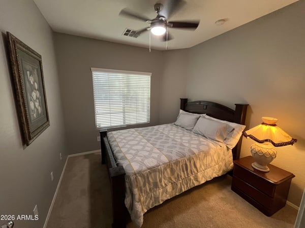 Comfortable bedroom featuring soft carpeting, ceiling fan, and natural light. A welcoming space that's ready to accommodate family, visitors, or remote work needs.