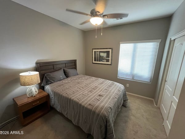 Bright secondary bedroom with neutral finishes, plush carpeting, ceiling fan, and closet space, providing flexibility for a guest room, nursery, or home office.