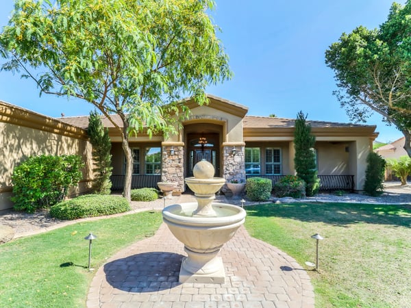 Inviting front entrance featuring professional landscaping, decorative stone columns, a beautiful courtyard fountain, and timeless architecture. This elegant entry reflects the quality and character found throughout this custom Glendale residence.