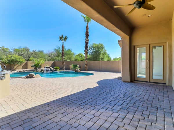 Large covered patio overlooks the sparkling PebbleTec play pool and beautifully landscaped backyard, creating an exceptional outdoor entertaining space complete with an outdoor grill and expansive paver hardscape.