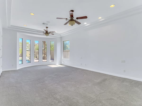 The spacious owner's suite offers tray ceilings, plush carpeting, ceiling fans, expansive windows, and plenty of room for a sitting area. A relaxing retreat within this beautifully maintained Glendale home.