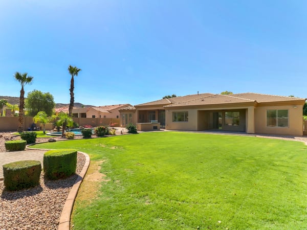 Expansive backyard featuring an oversized lawn, covered patio, sparkling pool, and mature landscaping perfect for entertaining and enjoying Arizona outdoor living in Glendale.