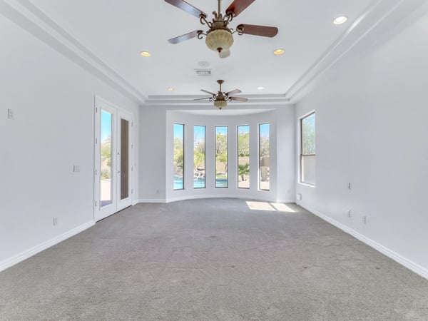 Spacious owner's suite offering a tray ceiling, abundant natural light, backyard views, and private patio access. This serene retreat provides the perfect place to unwind at the end of the day while enjoying the comfort of this custom Glendale home.
