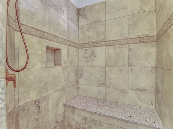 Relax in the beautifully finished walk-in shower featuring full-height tile, decorative accents, a built-in bench, and recessed storage niche. A spa-inspired feature that enhances this Glendale residence.