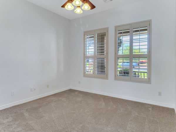 Plantation shutters, soft carpeting, high ceilings, and generous natural light make this secondary bedroom ideal for guests, family, or a home office. A flexible living space within this Glendale residence.