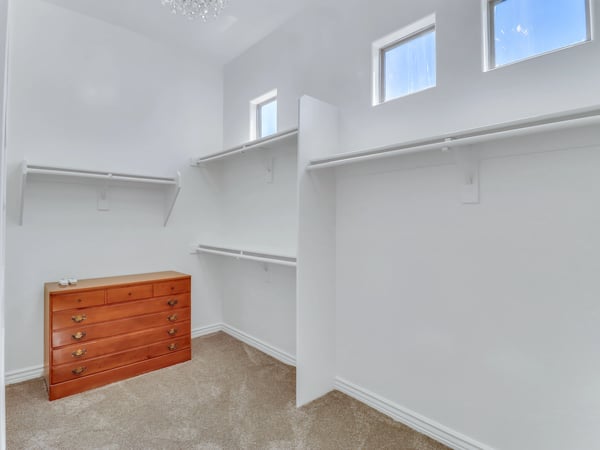 The spacious owner's closet offers custom shelving, built-in drawers, multiple hanging sections, and high ceilings that create a bright and functional storage area within this Glendale property.