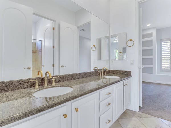 Well-appointed bathroom with dual sinks, granite counters, oversized mirror, abundant cabinetry, and quality fixtures designed for everyday convenience in this Glendale home.