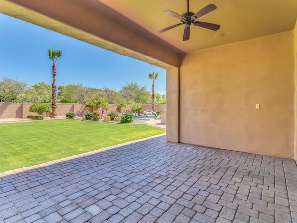 Covered outdoor patio with paver flooring, ceiling fan, and scenic views of the manicured backyard and sparkling pool. This Glendale home is ideal for entertaining guests or enjoying peaceful outdoor living.