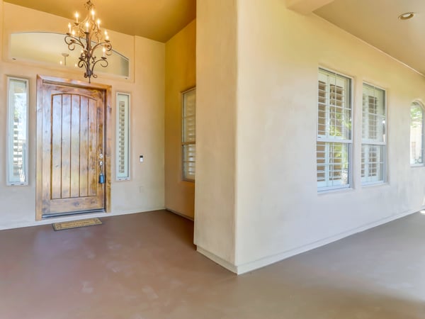 Attractive covered front entry featuring a handcrafted wood front door, decorative chandelier, plantation shutters, and timeless architectural details. This Glendale home welcomes guests with warmth and impressive curb appeal.