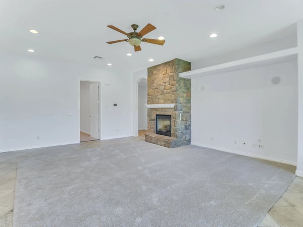Elegant living area centered around a striking stone fireplace with an open floor plan that flows effortlessly into the kitchen. A warm and welcoming space designed for relaxing or entertaining guests.
