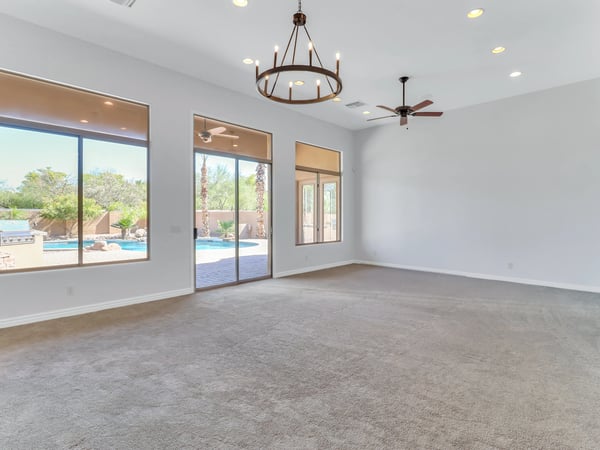 Spacious living area featuring high ceilings, recessed lighting, elegant chandelier, ceiling fan, and expansive glass doors opening directly to the backyard retreat in Glendale.