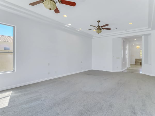 Spacious owner's suite featuring tray ceilings, dual ceiling fans, plush carpeting, recessed lighting, and a bright, open layout. This Glendale property delivers comfort and generous bedroom space.