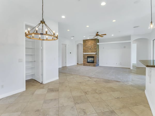 The open floor plan offers seamless flow between the dining area, kitchen, and family room with elegant lighting, recessed lighting, tile flooring, and a beautiful stone fireplace. A welcoming gathering space in this Glendale home.