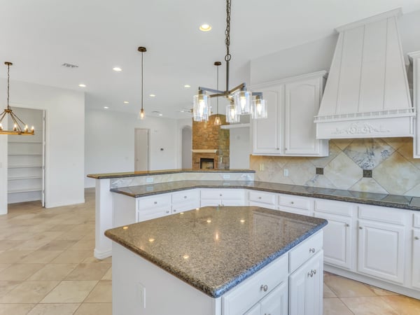 Decorative cabinetry, granite counters, a custom range hood, pendant lighting, and a raised breakfast bar create an elegant kitchen that opens effortlessly to the living areas of this Glendale home.