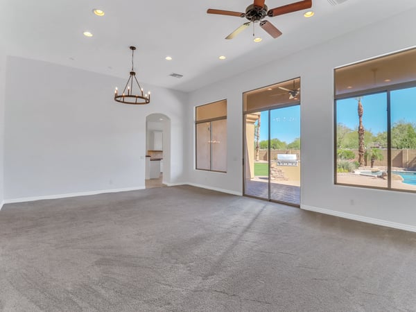 Open living room with soaring ceilings, abundant natural light, oversized windows, sliding glass doors, and seamless access to the covered patio and resort-style backyard in Glendale.