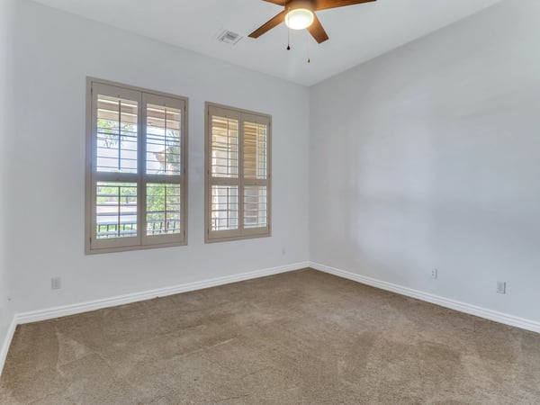 Inviting bedroom featuring plantation shutters, plush carpeting, ceiling fan, and bright natural light. This Glendale home offers comfortable guest accommodations with versatile living space.