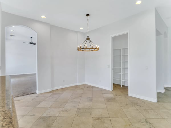 Elegant dining area featuring modern chandelier lighting, tile flooring, and an open connection to the kitchen and living spaces. This Glendale home offers a welcoming atmosphere for gatherings.