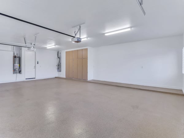 Finished three-car garage featuring epoxy flooring, built-in storage cabinets, bright lighting, and plenty of room for vehicles, tools, and recreational equipment. A practical and well-organized feature of this Glendale home.