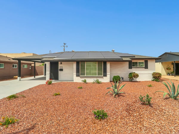Front exterior showcasing attractive desert landscaping, updated paint, covered entry, and rooftop solar panels that help improve energy efficiency. Enjoy low-maintenance living in this beautifully remodeled Phoenix lease.