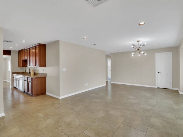 Open great room with contemporary lighting, recessed fixtures, oversized tile flooring, and a bright neutral color palette creates a comfortable setting for everyday living in this remodeled Phoenix rental.
