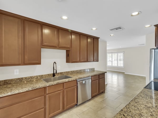Open kitchen with granite surfaces, stainless steel appliances, plentiful storage, and excellent connection to the living areas provides a practical and inviting heart of this remodeled Phoenix rental.