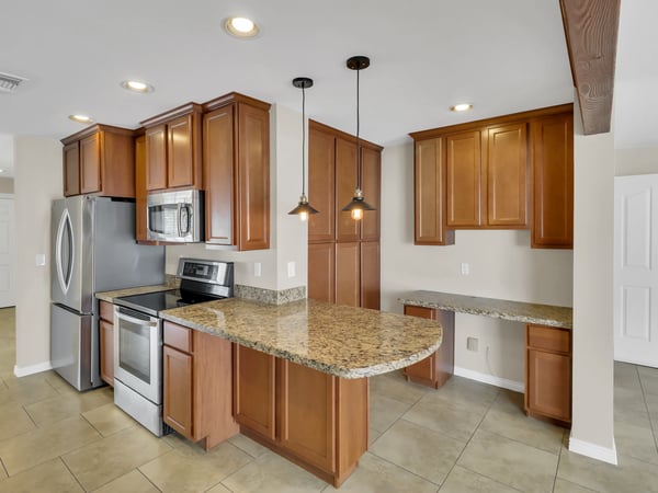 Spacious kitchen with a large granite breakfast bar, stainless steel appliances, custom cabinetry, and built-in workspace. This updated Phoenix rental blends functionality with modern style.