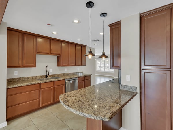 Bright kitchen showcasing granite surfaces, pendant lighting, stainless steel appliances, and plentiful cabinetry with views into the adjoining living areas. Perfect for today's active lifestyle in Phoenix.