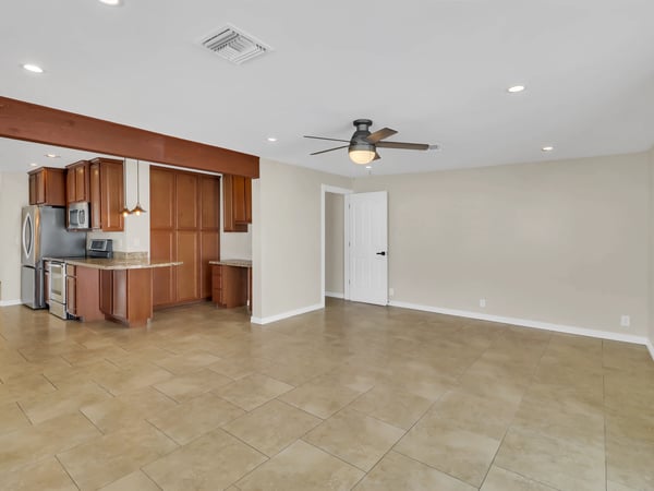 Expansive living area featuring neutral finishes, tile flooring, ceiling fan, and direct access to the updated kitchen. This Phoenix rental offers versatile space for relaxing, entertaining, or working from home.