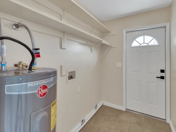 Functional utility room with built-in shelving, utility hookups, and additional storage for household essentials. This practical feature adds everyday convenience to this remodeled Phoenix rental.
