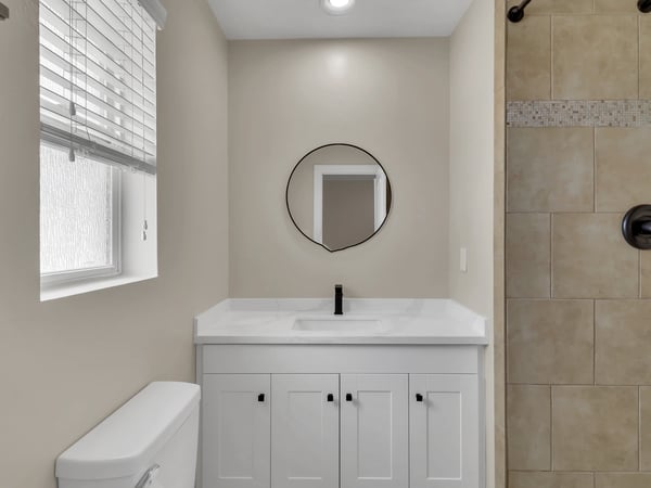 Beautifully updated bathroom with quartz countertop, white shaker cabinetry, matte black fixtures, and designer tile accents. A fresh, modern upgrade within this remodeled Phoenix rental.