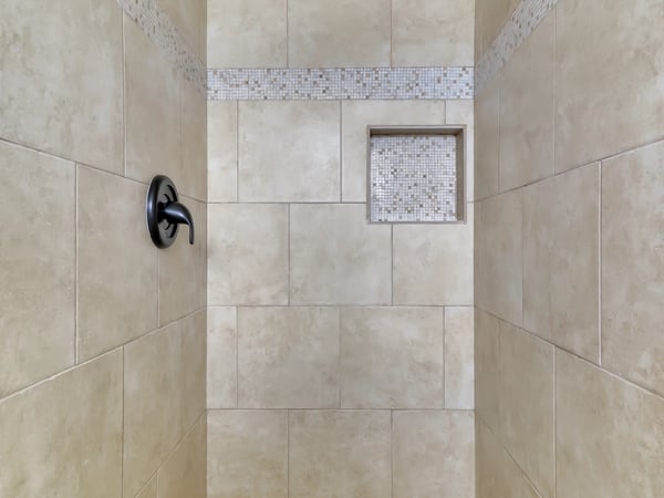 Elegant walk-in shower with oversized tile, mosaic accent band, recessed storage niche, and rainfall showerhead. This spa-inspired feature elevates the appeal of this updated Phoenix rental.