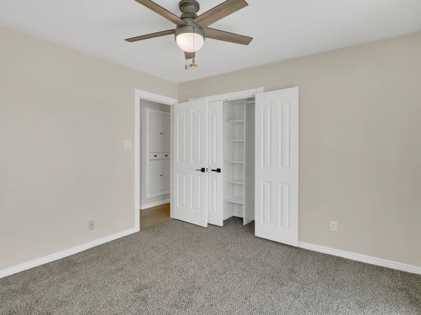 Comfortable bedroom with soft carpeting, ceiling fan, ample closet storage, and neutral finishes. This inviting room provides flexibility for family, guests, or a home office in Phoenix.